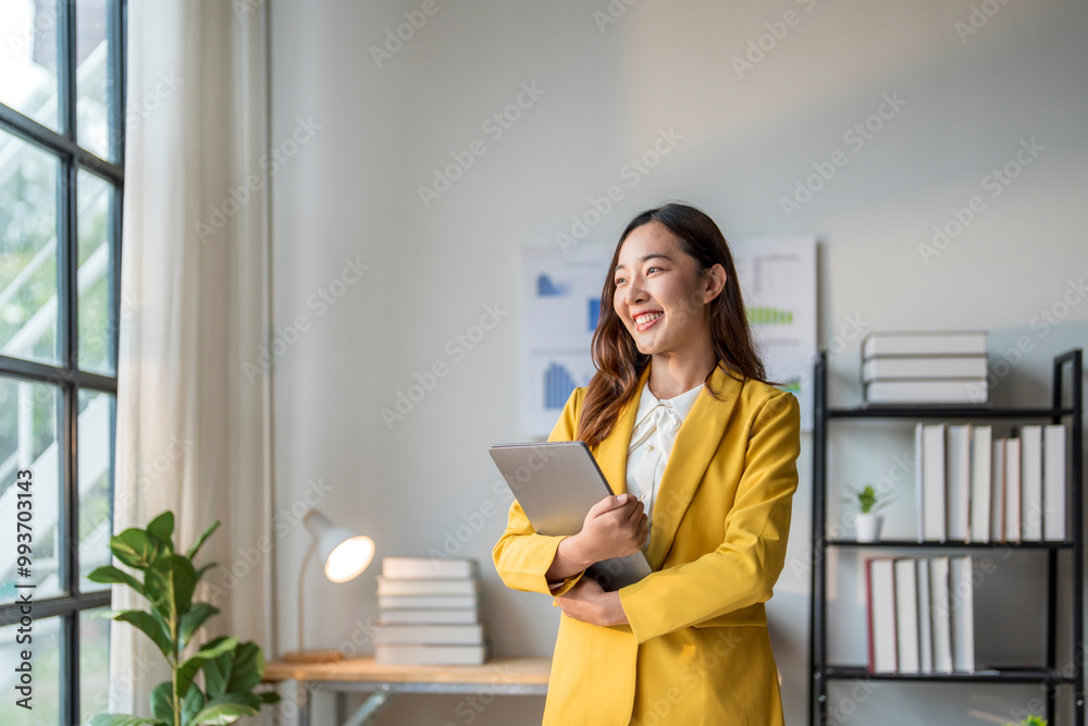 Young businesswoman holding laptop smiling and looking out the window in office