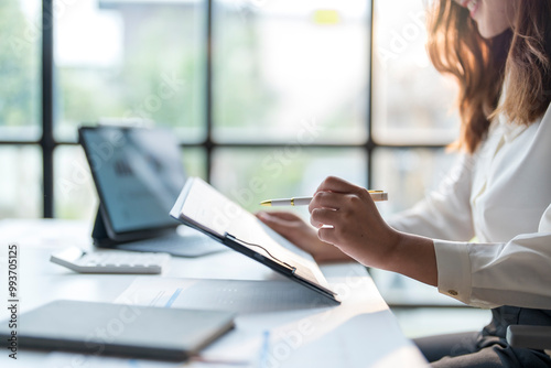 Businesswoman analyzing financial chart on digital tablet and taking notes