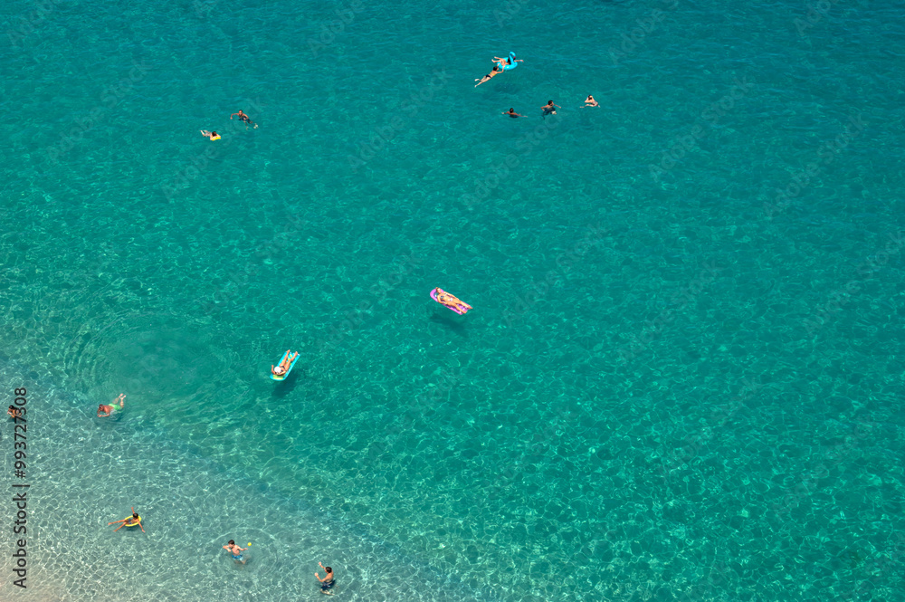 Aerial view of sandy beach with swimming people in sea with transparent blue water in summer. Aerial view of sandy beach with swimming people in sea with transparent blue water in summer.