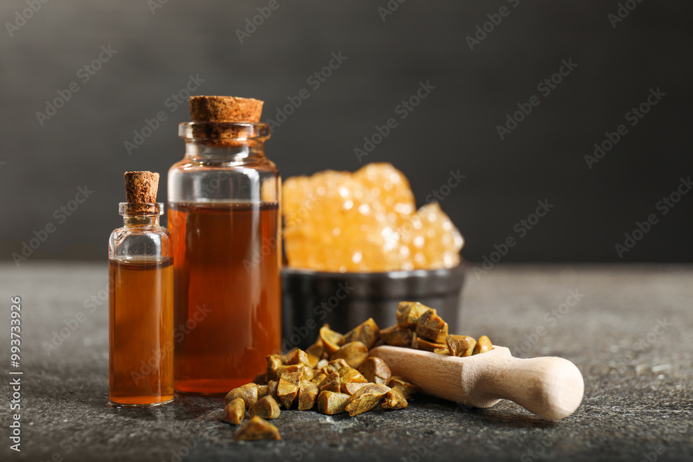 Honey tincture and scoop with propolis granules on grey textured table, closeup. Alternative medicine
