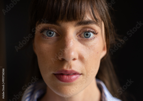 Close-up of woman with blue eyes and bangs, looking directly at camera