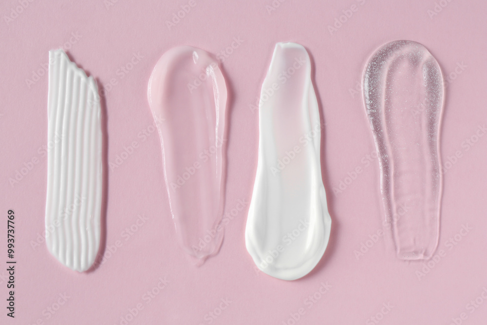 Smears of different cosmetic products on pink background, flat lay Smears of different cosmetic products on pink background, flat lay