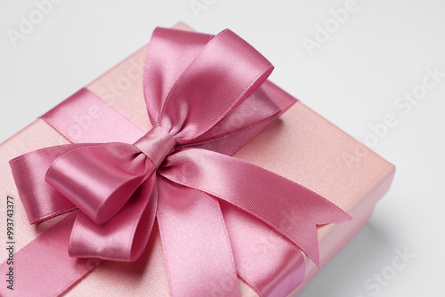 Gift box with pink bow on light grey background, closeup