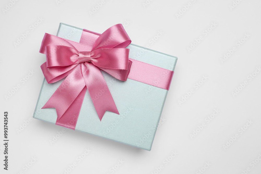 Gift box with pink bow on light grey background, top view. Space for text Gift box with pink bow on light grey background, top view. Space for text