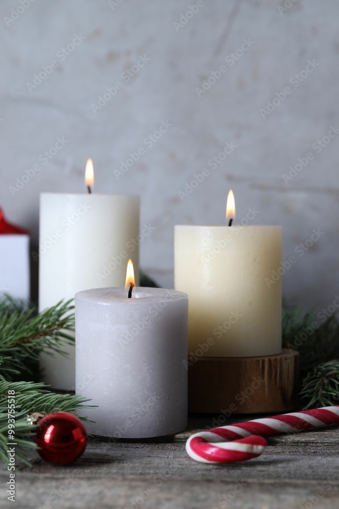 Burning candles, Christmas decor and fir tree branches on wooden table, closeup Burning candles, Christmas decor and fir tree branches on wooden table, closeup