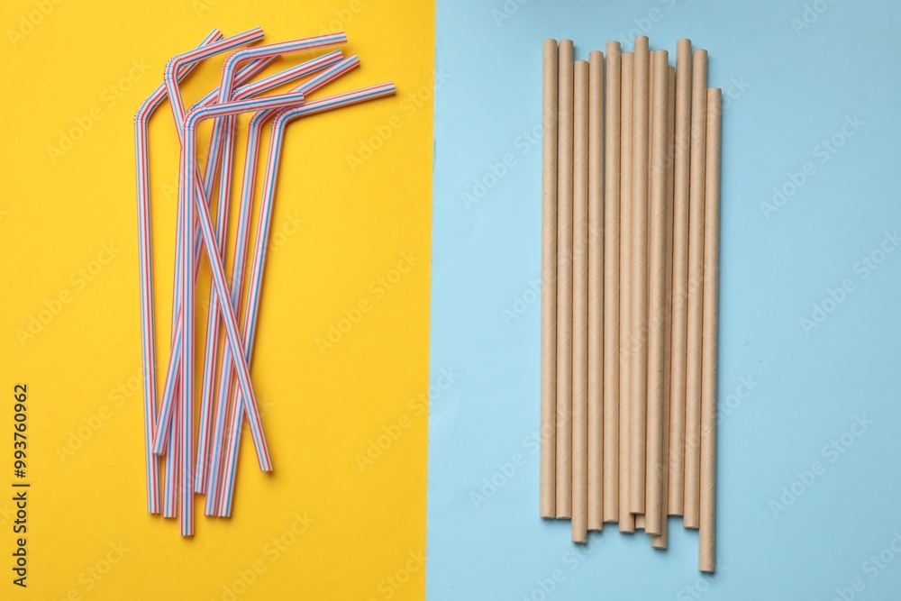 Plastic and bamboo drinking straws on color background, flat lay