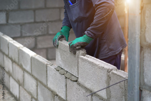 masonry worker make concrete wall by cement block and plaster at construction site