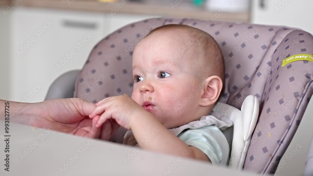 baby boy eats lunch at a feeding table in the kitchen. happy family child dream concept. mother feeds the baby in the kitchen. Baby child eats lunch in the kitchen lifestyle baby boy eats lunch at a feeding table in the kitchen. happy family child dream concept. mother feeds the baby in the kitchen. Baby child eats lunch in the kitchen lifestyle