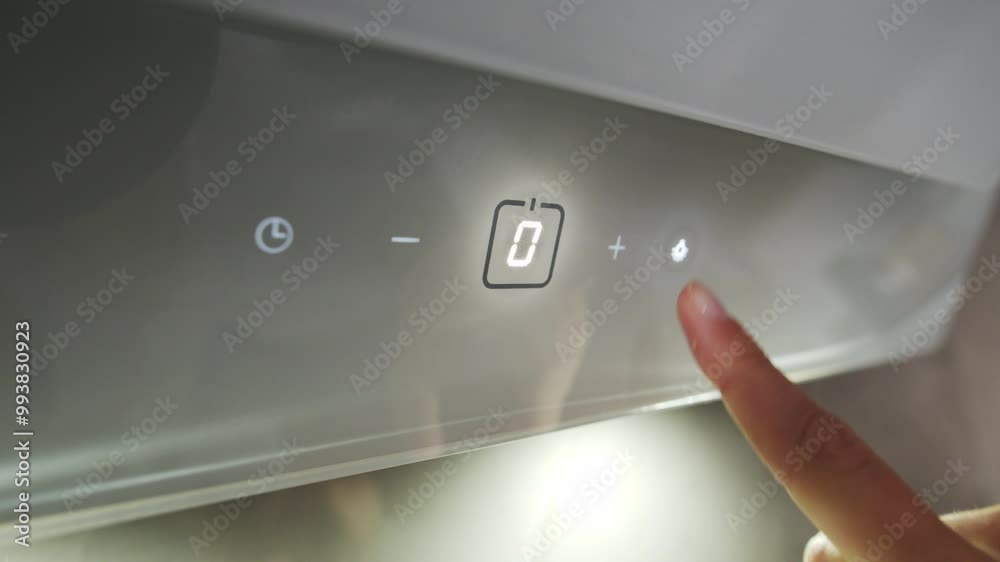 The man presses the buttons on the control panel of the new modern kitchen hood The man presses the buttons on the control panel of the new modern kitchen hood