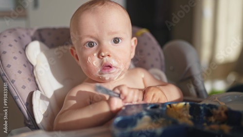 baby dirty eats. happy family a child toddler concept. baby dirty lifestyle sitting messing with food at the table for feeding in the kitchen. grimy toddler in the kitchen photo