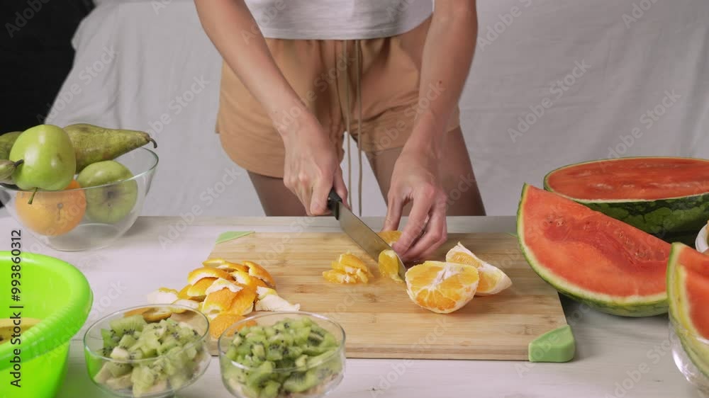 Hands of young woman european cutting orange with kitchen knife for making fruit salad, front side view medium shot. Healthy lifestyle concept, raw food diet, cooking at home, refreshing Hands of young woman european cutting orange with kitchen knife for making fruit salad, front side view medium shot. Healthy lifestyle concept, raw food diet, cooking at home, refreshing