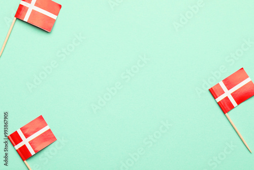 Small paper flags of Denmark on turquoise background, top view. Space for text
