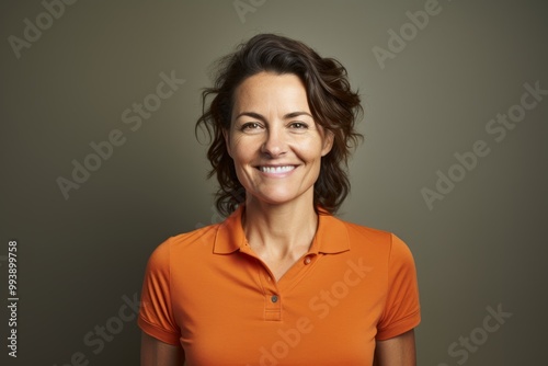 Portrait of a smiling woman in her 40s wearing a sporty polo shirt isolated in minimalist or empty room background