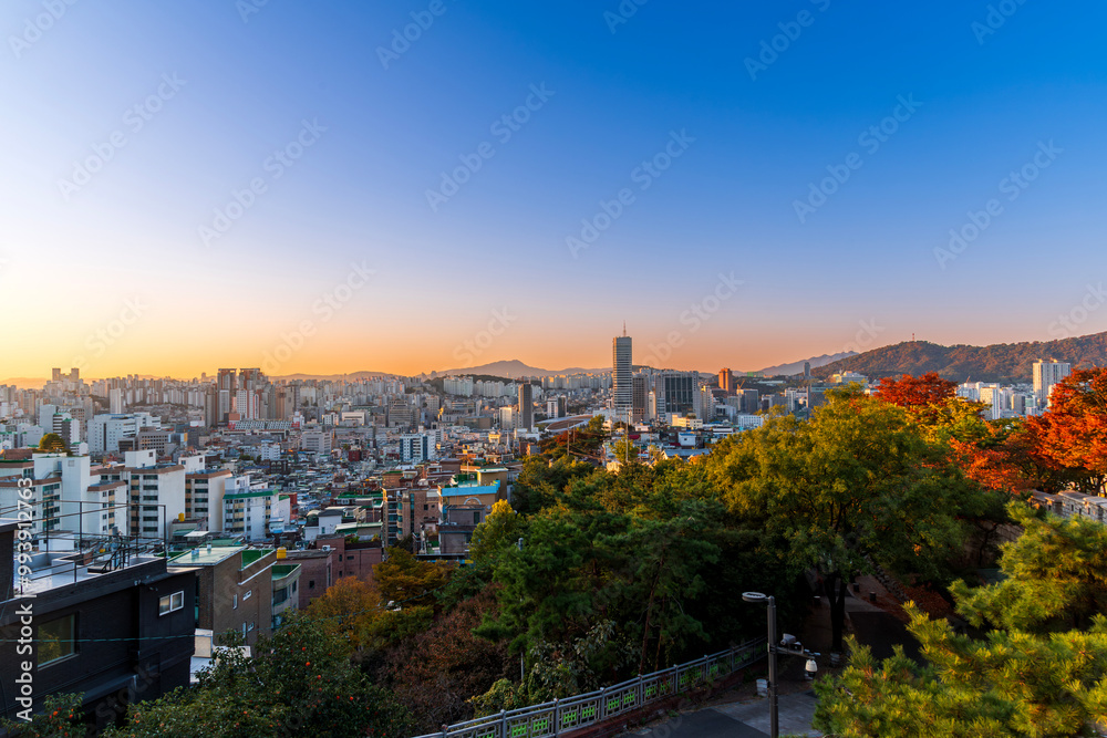 Sunset of Seoul cityscape with high rise office buildings and skyscrapers and cityFortress wall of Heunginjimun with autumn colorful park, Seoul, South Korea in autumn season