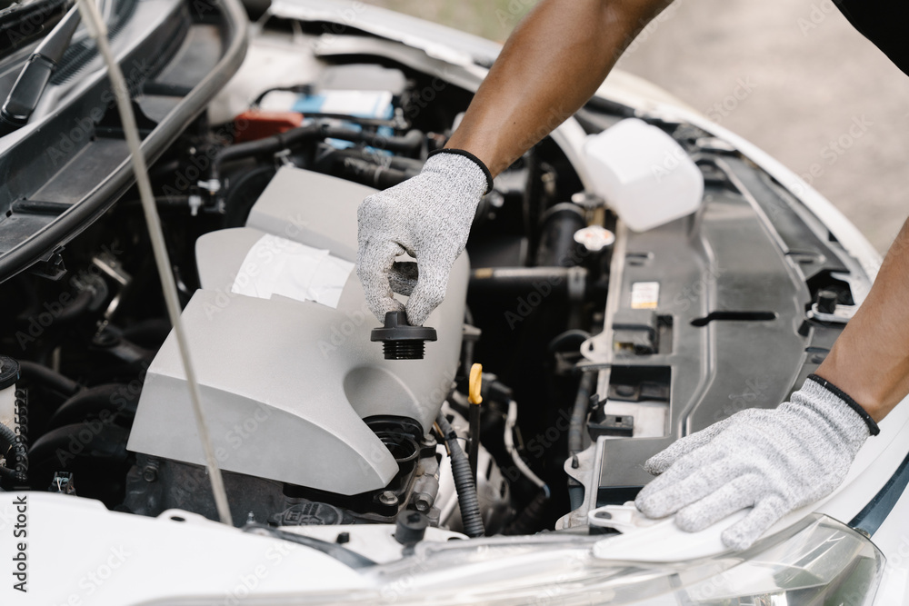 Close-up of Mechanic Checking Engine Oil: A pair of gloved hands carefully checks the engine oil level, ensuring the car is running smoothly. Close-up of Mechanic Checking Engine Oil: A pair of gloved hands carefully checks the engine oil level, ensuring the car is running smoothly.