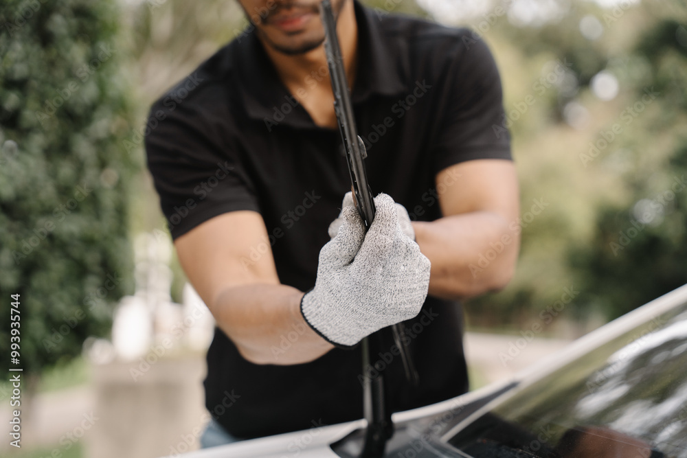 Φωτογραφία Man Replacing Windshield Wiper Blade: A close-up shot of a man's hands wearing gray work gloves as he replaces a windshield wiper blade on a car, showcasing maintenance and auto care