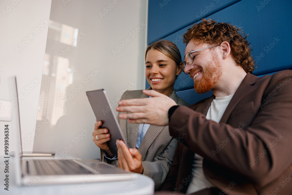 Two enthusiastic professionals share a productive moment while using digital devices in a contemporary workspace Two enthusiastic professionals share a productive moment while using digital devices in a contemporary workspace