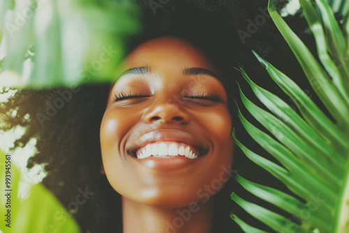  Afro-American young woman smiles joyfully amidst lush greenery, radiating confidence and natural beauty. Her carefree expression reflects a serene connection with nature, exuding positivity and warmt photo