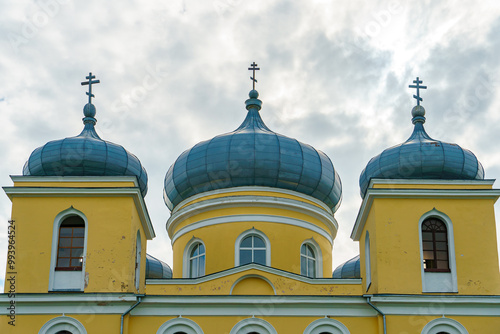 An unusual Catholic church building with three domes and crosses. The walls of the Catholic church are yellow. photo