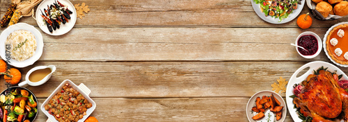 Thanksgiving turkey dinner. Top down view double border on a rustic wood table banner background. Turkey, mashed potatoes, stuffing, pumpkin pie and sides.