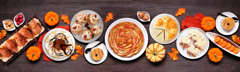 Autumn desserts table scene with a variety of gourmet fall sweet foods. Top view over a dark wood banner background.
