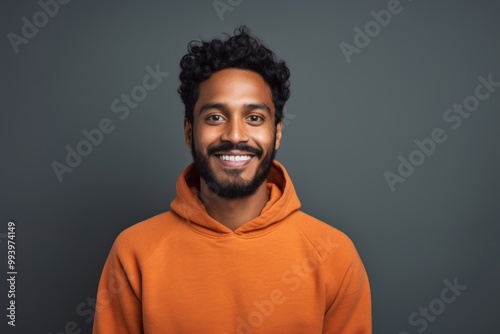 Portrait of a glad indian man in his 20s wearing a thermal fleece pullover in front of solid color backdrop