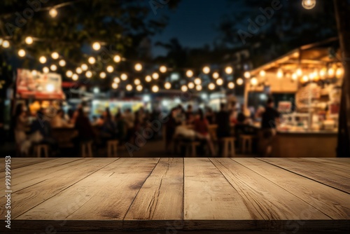 Empty wooden table top with blurred food truck and people at night time