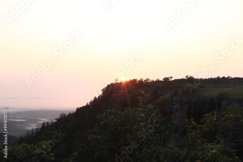 sunset or sunrise over the mountains with a valley and trees