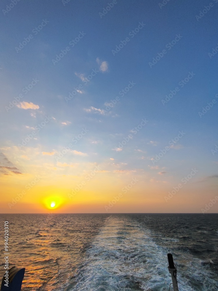 Beautiful sunrise over calm open sea, captured from a ferry boat. Golden light reflects on the water, with soft waves and vibrant sky, evoking tranquility and adventure at sea. Beautiful sunrise over calm open sea, captured from a ferry boat. Golden light reflects on the water, with soft waves and vibrant sky, evoking tranquility and adventure at sea.