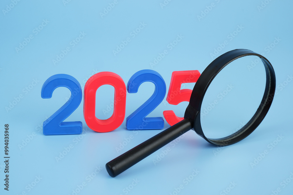 Magnifying glass and numbers 2025 on blue background. Prognosis for year 2025. Magnifying glass and numbers 2025 on blue background. Prognosis for year 2025.