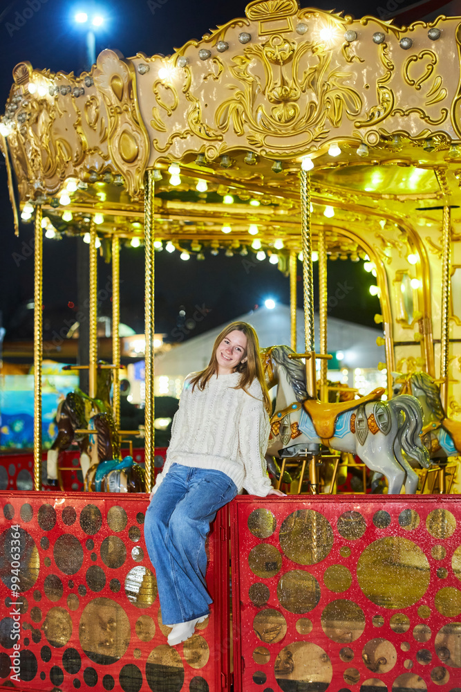 Stylish young girl on the street near the carousel. Night time of the day. Stylish young girl on the street near the carousel. Night time of the day.