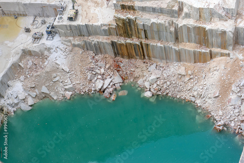 Machines working in the depths of a marble quarry in Vila Viçosa, Alentejo, Portugal. Industrial equipment extracting marble blocks amidst a rugged landscape of stone and dust.
