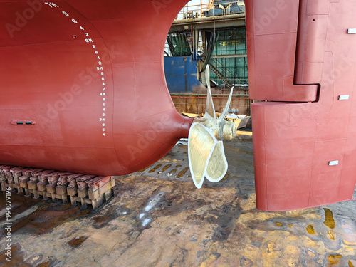 The rear end and propeller of a huge seagoing vessel in dry dock undergoing repairs photo