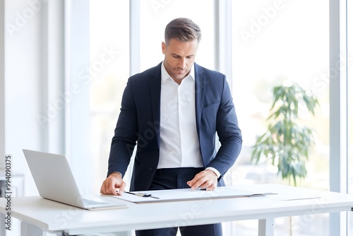 Handsome Businessman Working Diligently at Sleek Modern Office Desk with Natural Light