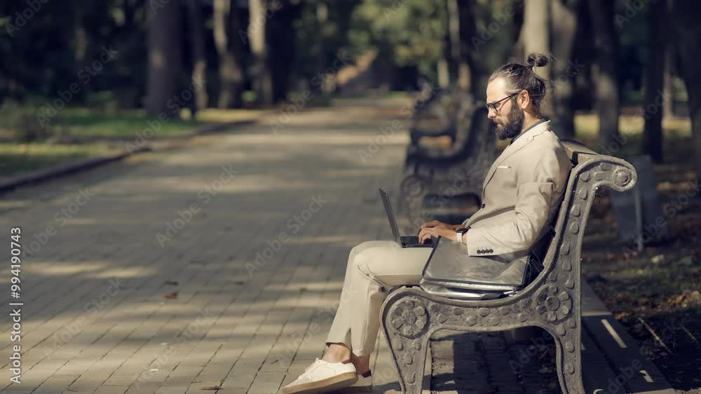 Man working remotely on laptop while sitting on park bench Man working remotely on laptop while sitting on park bench