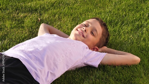 smiling child lying green grass. happy face child illuminated by sunlight.