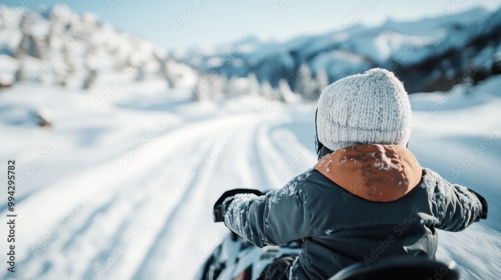 A scenic image featuring a child bundled in winter clothes riding a snowmobile through snow-covered terrain, with mountains and clear skies in the backdrop, representing freedom and adventure. A scenic image featuring a child bundled in winter clothes riding a snowmobile through snow-covered terrain, with mountains and clear skies in the backdrop, representing freedom and adventure.