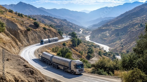 Convoy of oil trucks transporting crude oil on winding mountain road amidst scenic landscape