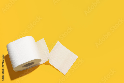 Roll of toilet paper on yellow background