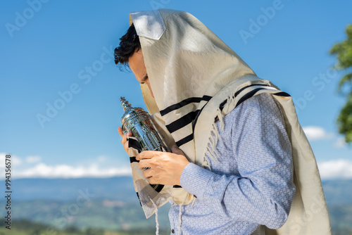 Young Jewish Man Holding a Sefer Torah While Praying Under His Tallit photo