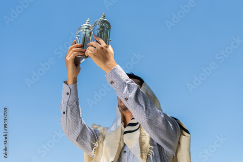 Young Jewish Man Raising a Sefer Torah to the Sky in Celebration of Simchat Torah photo