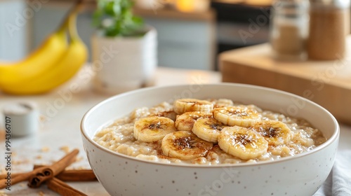 A hearty bowl of oatmeal with caramelized banana slices and cinnamon, set on a light ceramic dish with a minimalist kitchen in the background