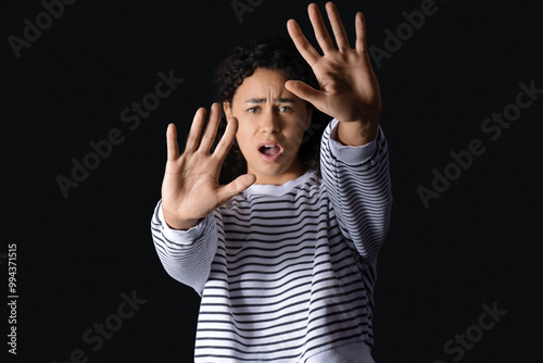 Young African-American woman having panic attack on black background
