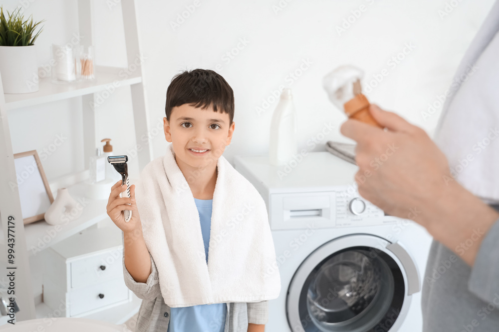 Happy father and his little son holding brush with razor in bathroom Happy father and his little son holding brush with razor in bathroom