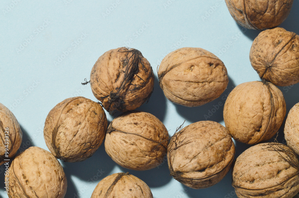 minimal close up whole walnuts on blue background, copy space, frame, top down view minimal close up whole walnuts on blue background, copy space, frame, top down view