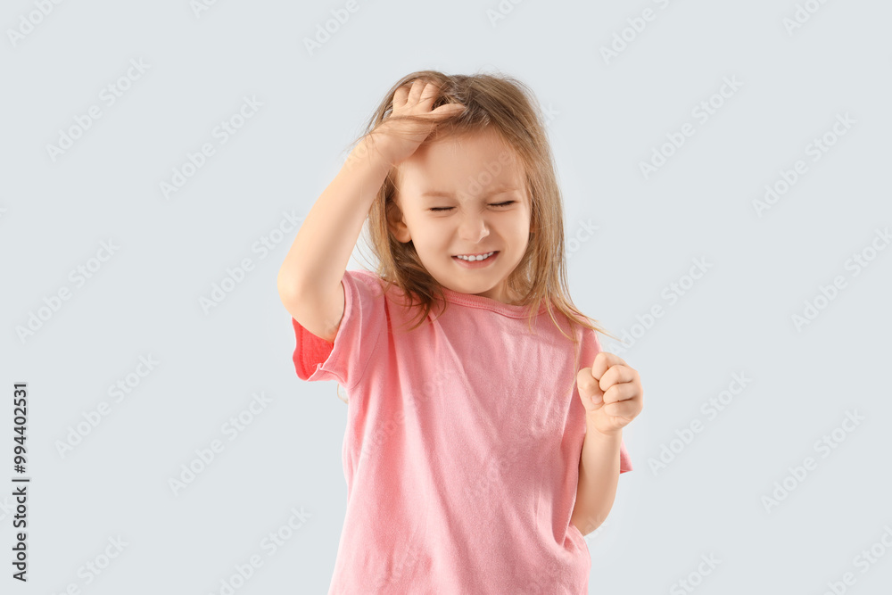 Little girl with pediculosis scratching her head on light background Little girl with pediculosis scratching her head on light background