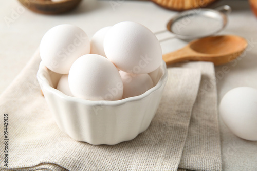 Bowl with raw chicken eggs on white background