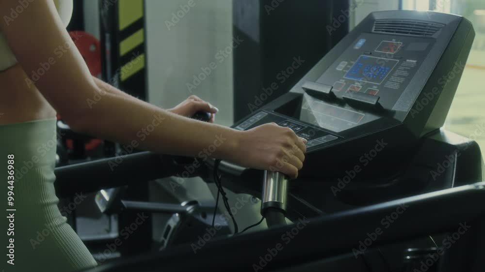 Close up view of unrecognizable slim woman in sportswear setting mode while walking on treadmill in gym Close up view of unrecognizable slim woman in sportswear setting mode while walking on treadmill in gym