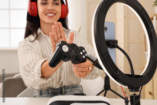 Female blogger in headphones with game pad recording video at home, closeup