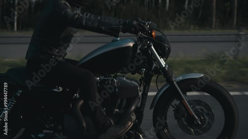 Man in black helmet and black clothes rides motorcycle on the highway.